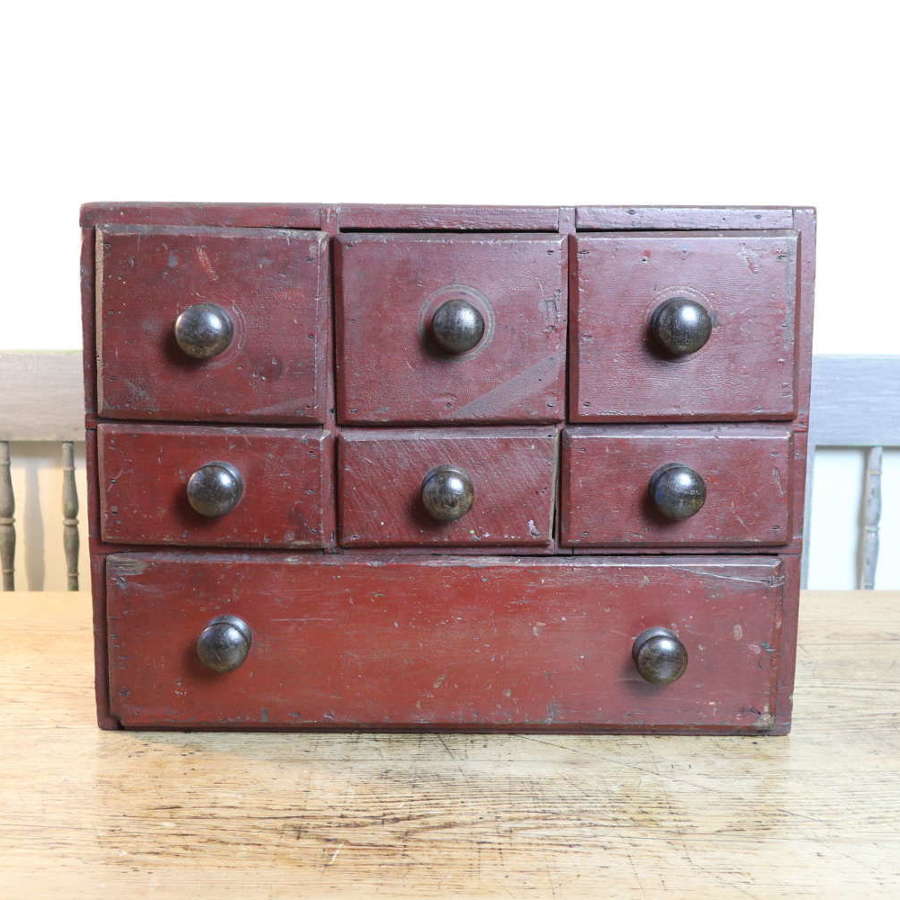 19th Century table top iron red painted pine bank of drawers
