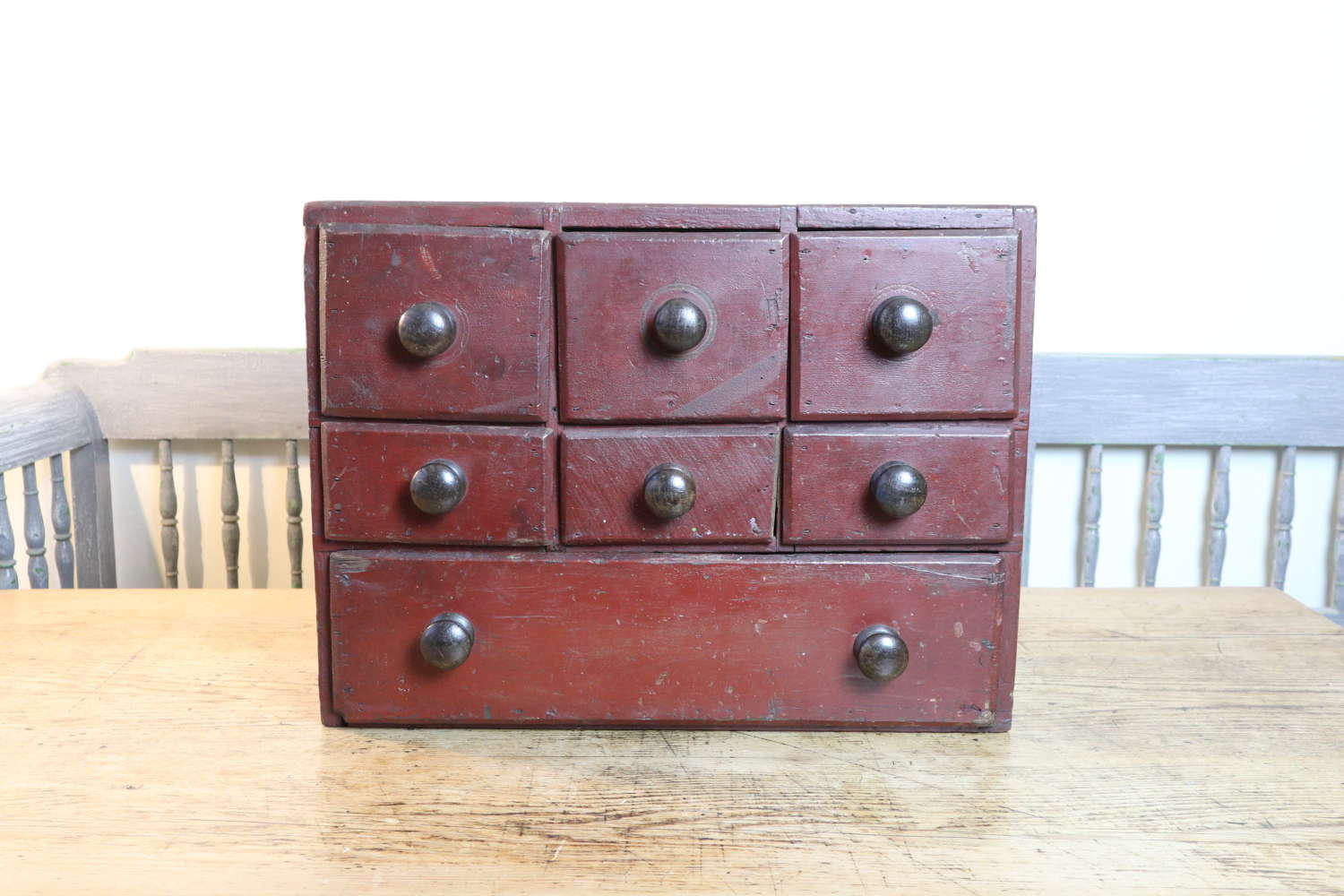 19th Century table top iron red painted pine bank of drawers